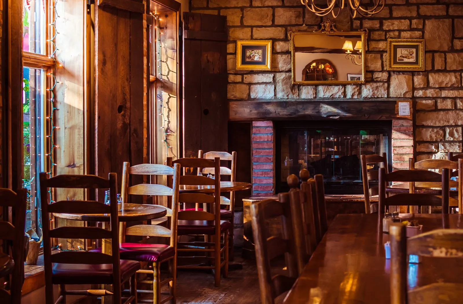 Warm wooden café interior with stone fireplace, wooden decor, and cozy ambiance.